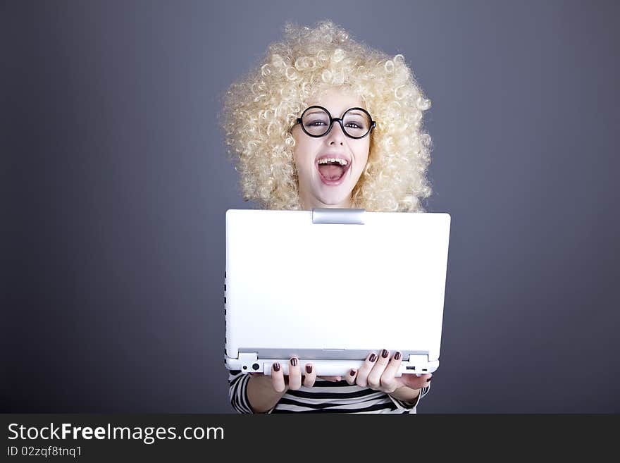 Portrait of funny girl in blonde wig with laptop. Studio shot.