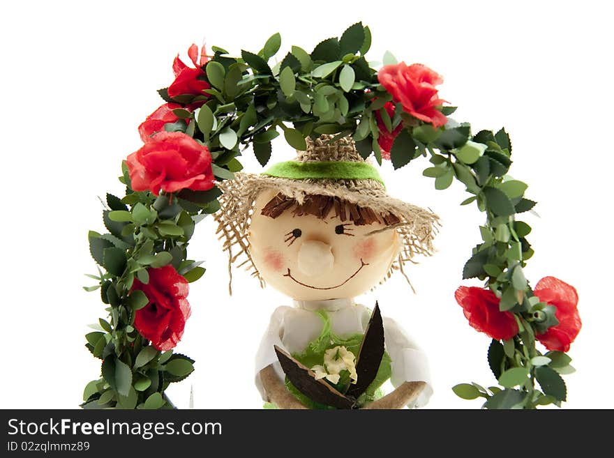 Straw doll behind wreath with roses