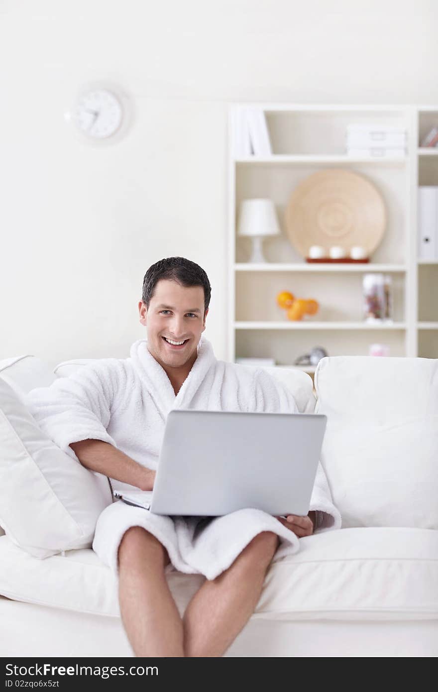 A young man in a white robe with laptop. A young man in a white robe with laptop