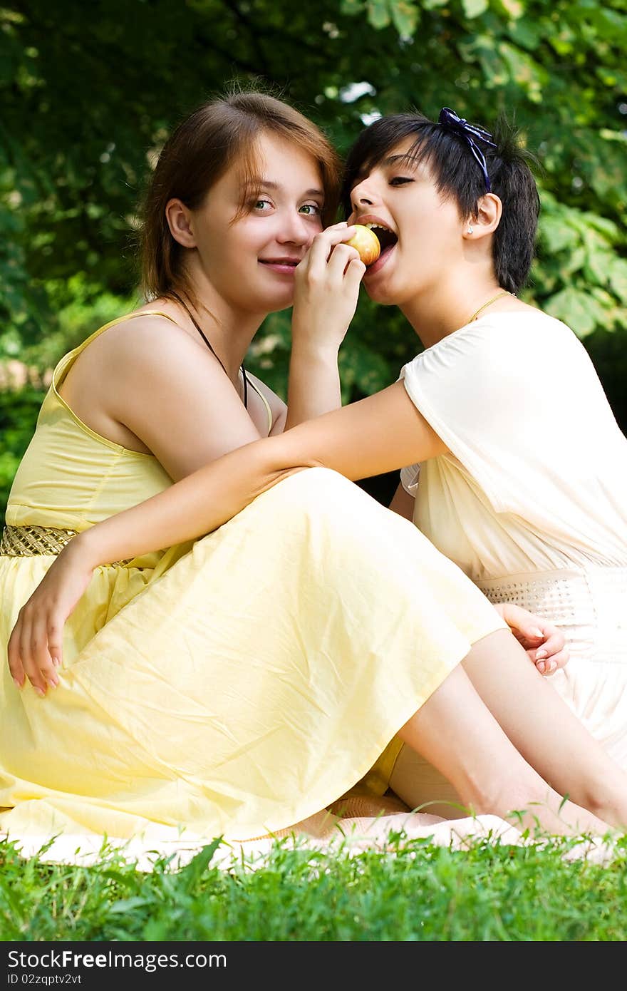 Two teen girls eating an apple