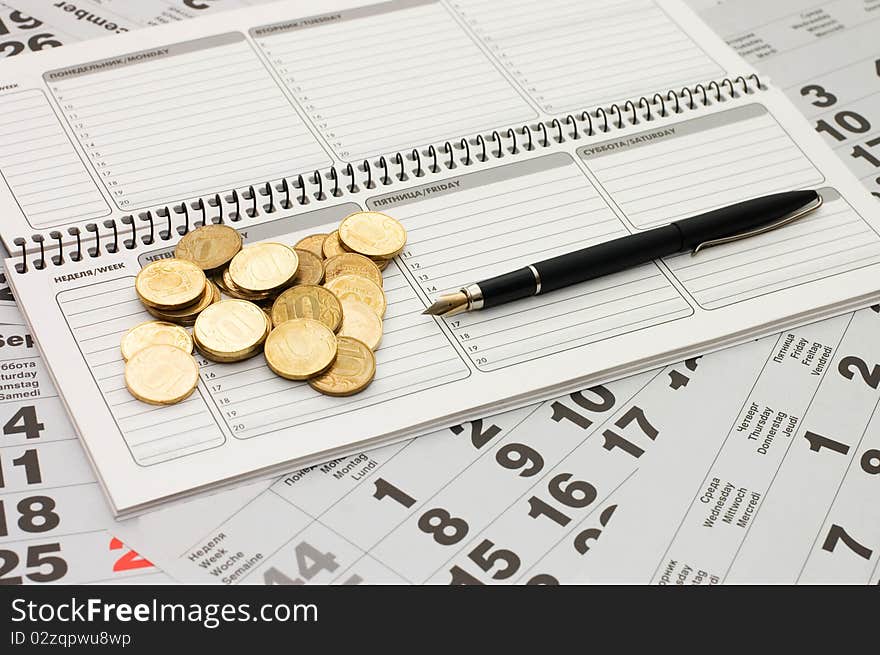 Sheets Of A Calendar With Coins And A Notebook