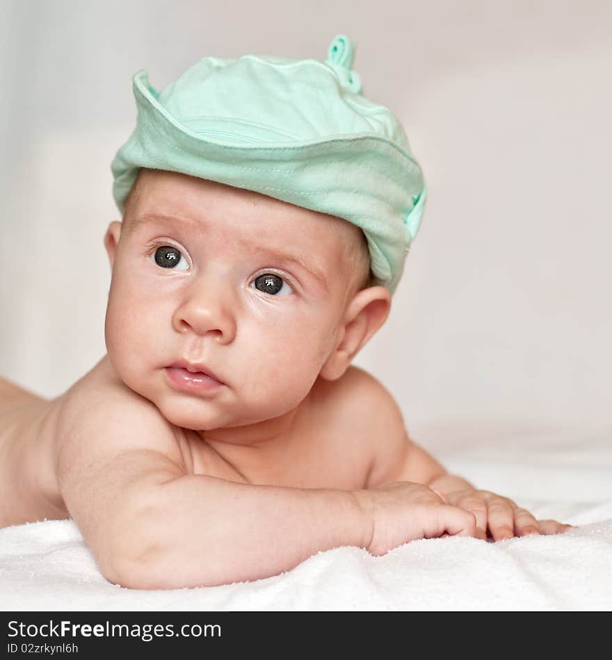 Baby in a cap lying on the bed