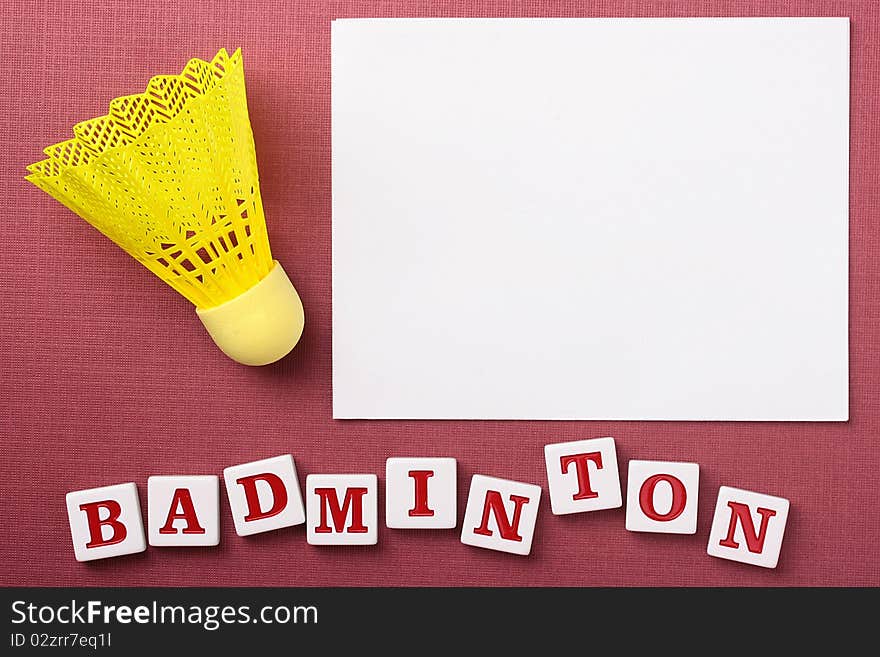 A yellow synthetic badminton shuttlecock next to a white piece of paper to which you can add your text.