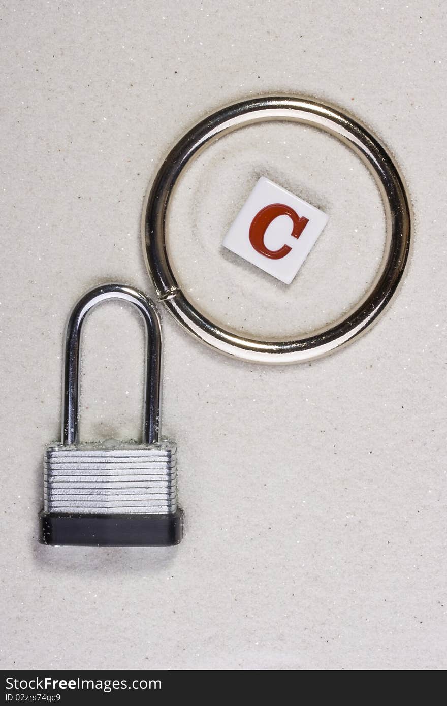 Copyright symbol on sand next to a metal lock.