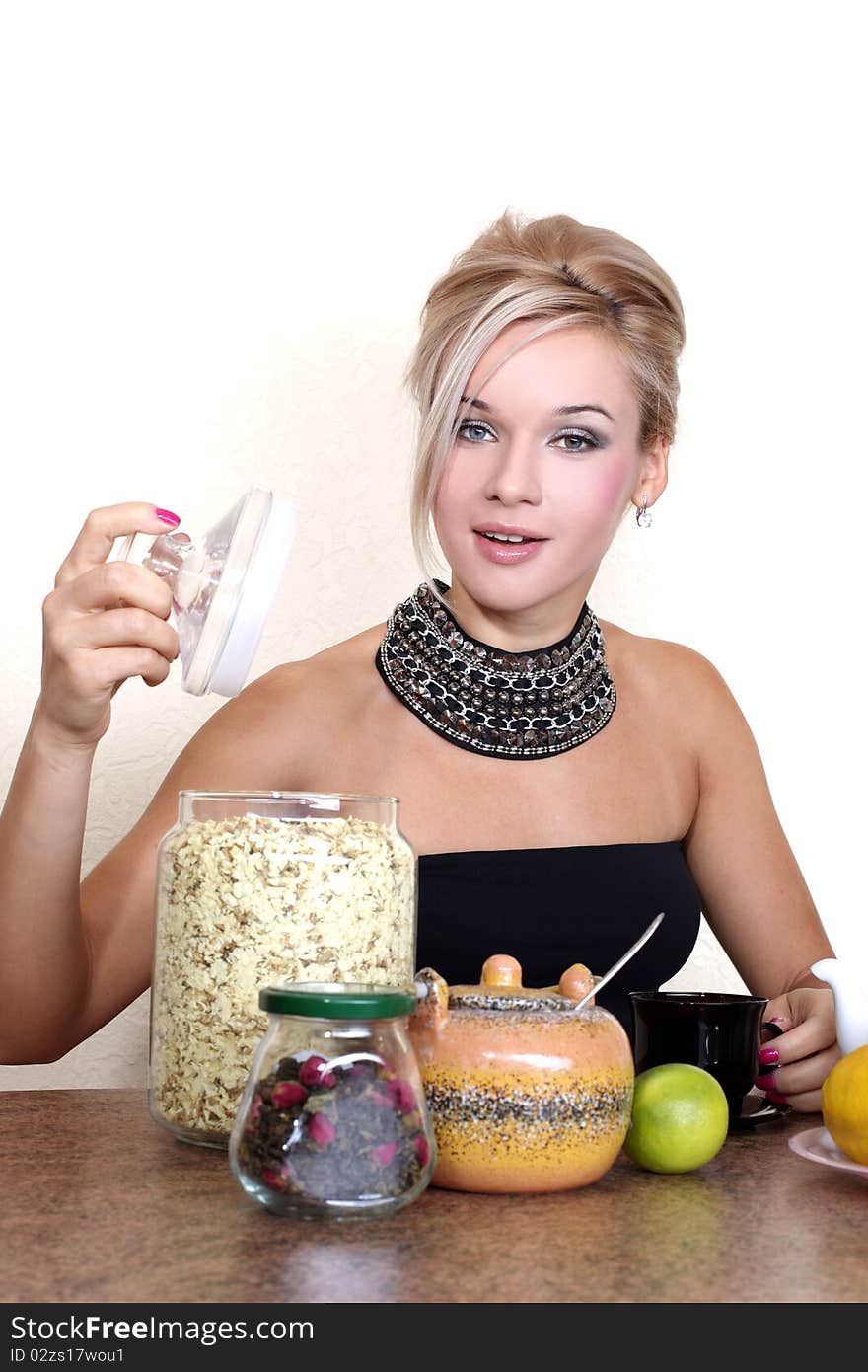 Woman with cup of hot drink, lemon, lime, tea, jasmin petals and autumn flowers against yellow wall at home. Woman with cup of hot drink, lemon, lime, tea, jasmin petals and autumn flowers against yellow wall at home