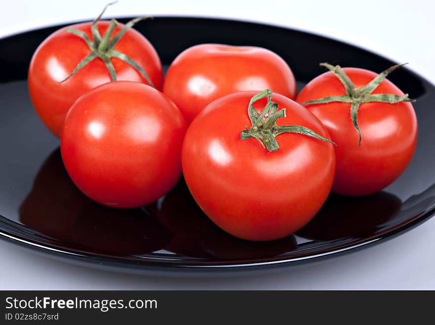 Red tomatoes on black plate