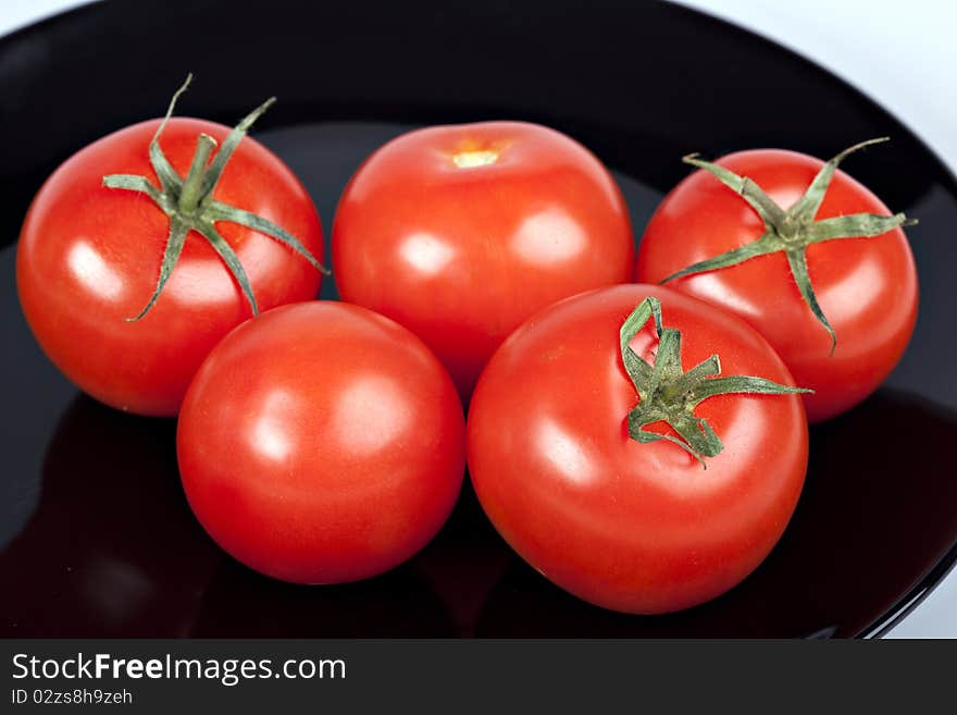 Red tomatoes on black plate