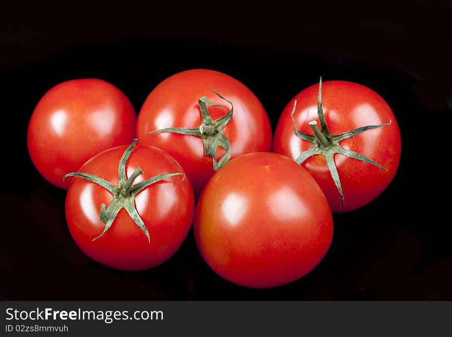 Red tomatoes on black background