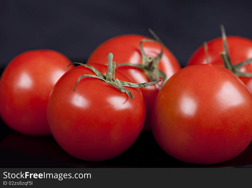 Red tomatoes on black background