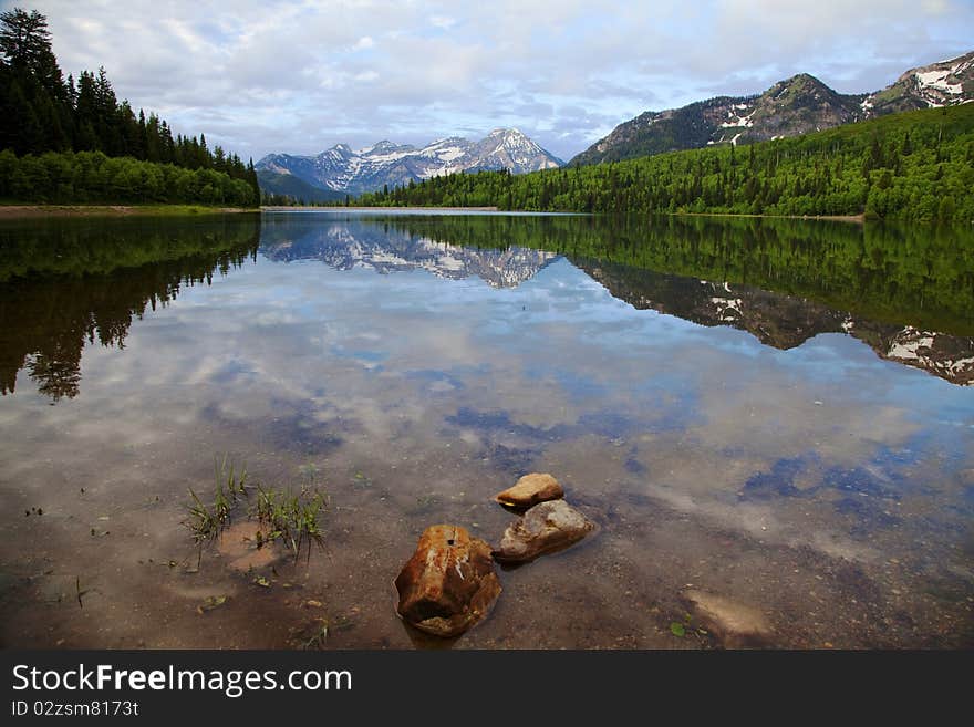 Mountain lake in the Spring with clouds with snow covered mountains reflected in the lake