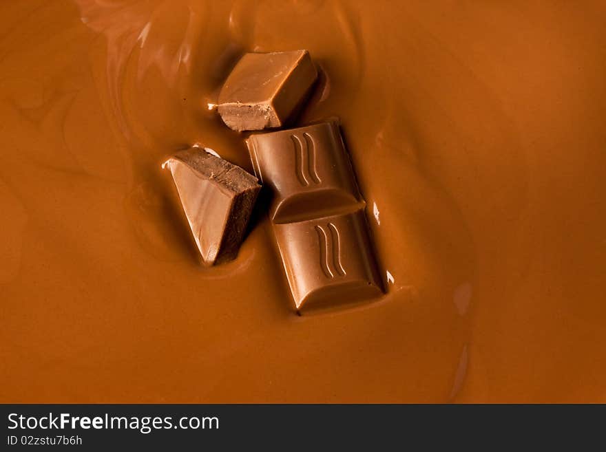 Liquid chocolate with individual pieces slowly sinking into it. Liquid chocolate with individual pieces slowly sinking into it