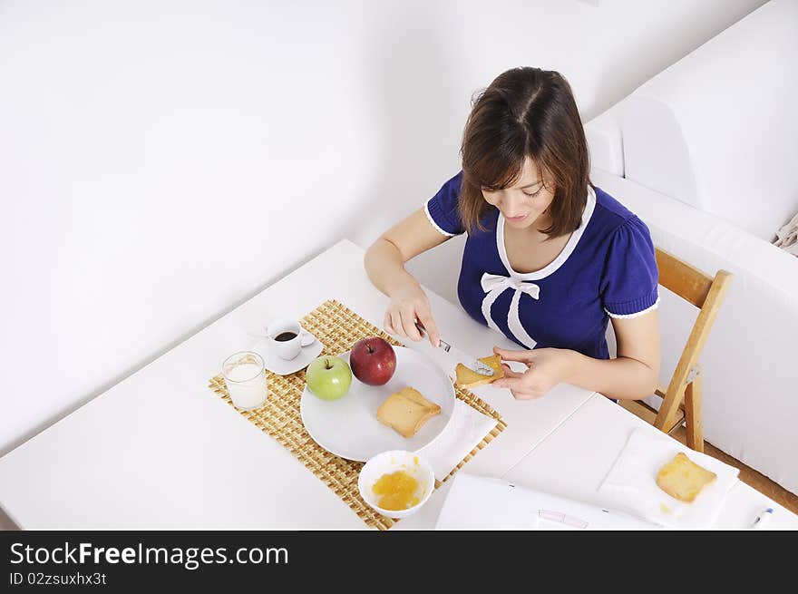 Young woman in breakfast, eating and using laptop. Young woman in breakfast, eating and using laptop