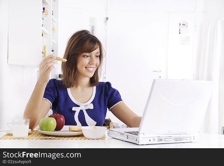 Young woman in breakfast, eating and using laptop. Young woman in breakfast, eating and using laptop