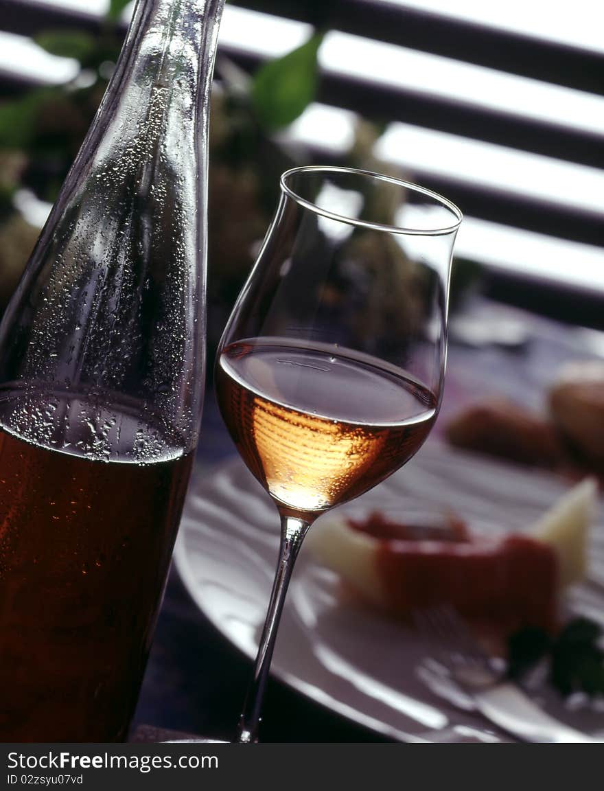 Glass and bottle of rose wine and food in the background. Glass and bottle of rose wine and food in the background