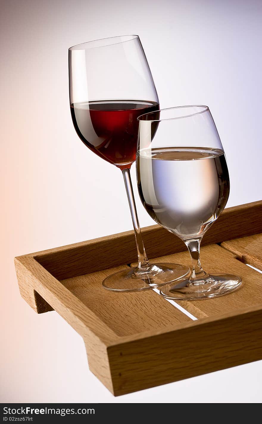 Glasses of red wine and water on wooden tray