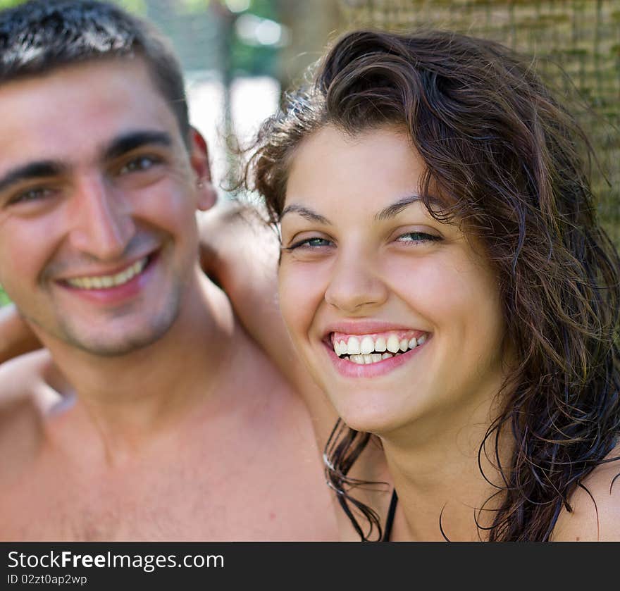 The couple laughing happily sitting on the sea under a palm tree. The couple laughing happily sitting on the sea under a palm tree