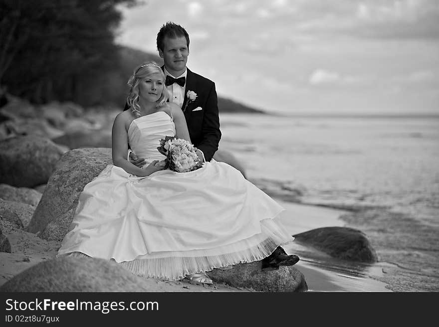 Wedding couple sitting on a stone by the ocean. Wedding couple sitting on a stone by the ocean