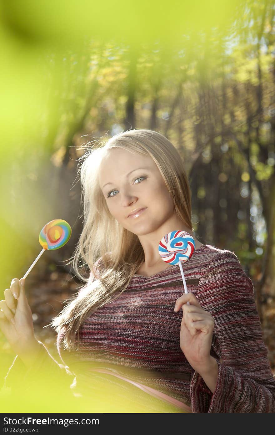 Young beautiful woman eating candy lollipops. Blurred background.