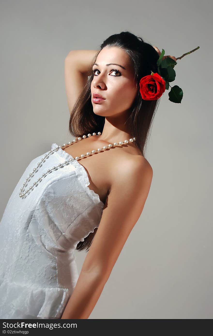 Young woman in a white dress holding a red rose