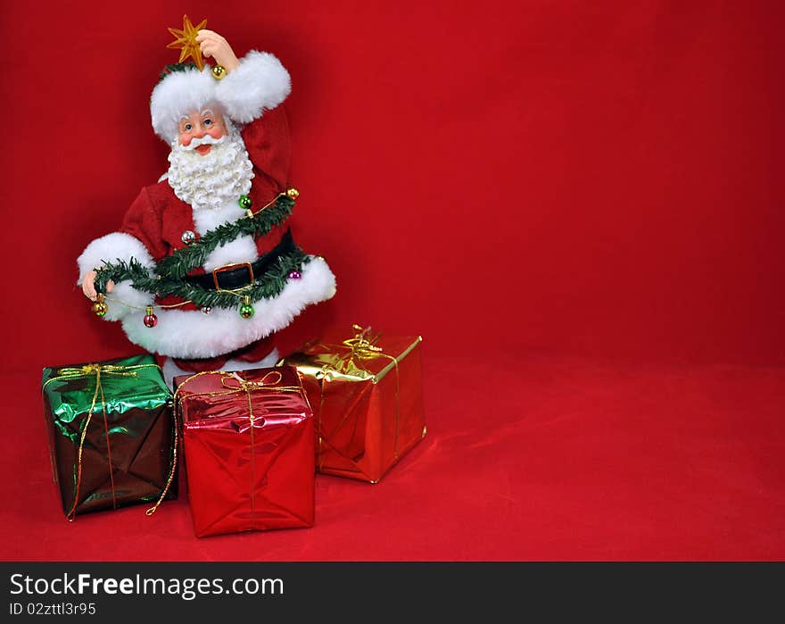 Santa trimming tree with presents on red background