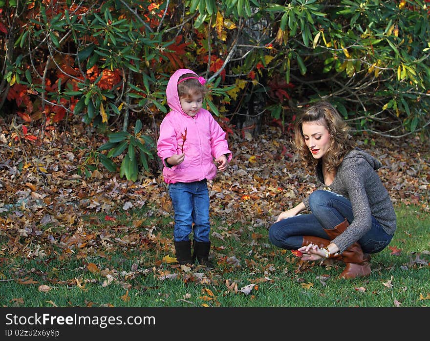 Mother and girl are playing with fall leaves