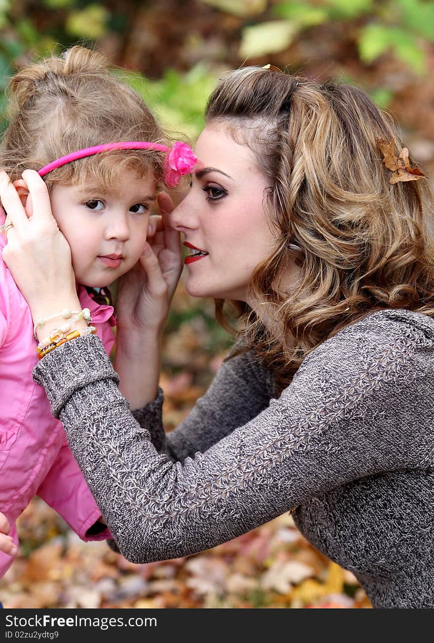 Mother and girl are playing with fall leaves