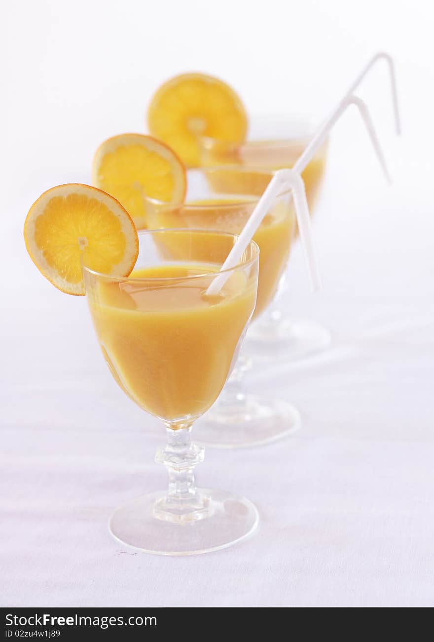 Three orange juice with slice of orange