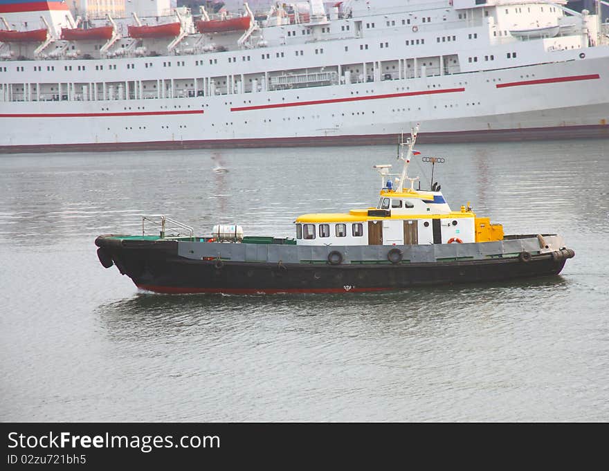 Boat with a yellow roof in the Japanese sea against the white ship