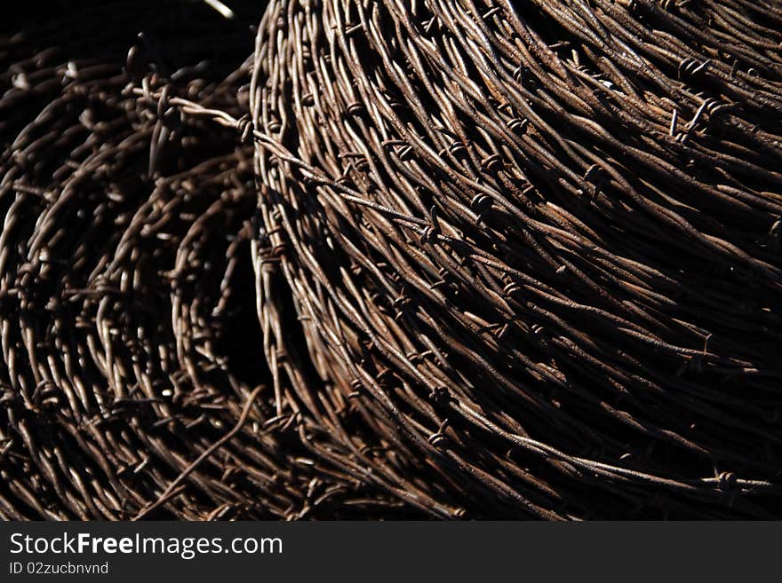 Rusted abandoned barbed wire, in rolls, left in a junk pile in the middle of a field.