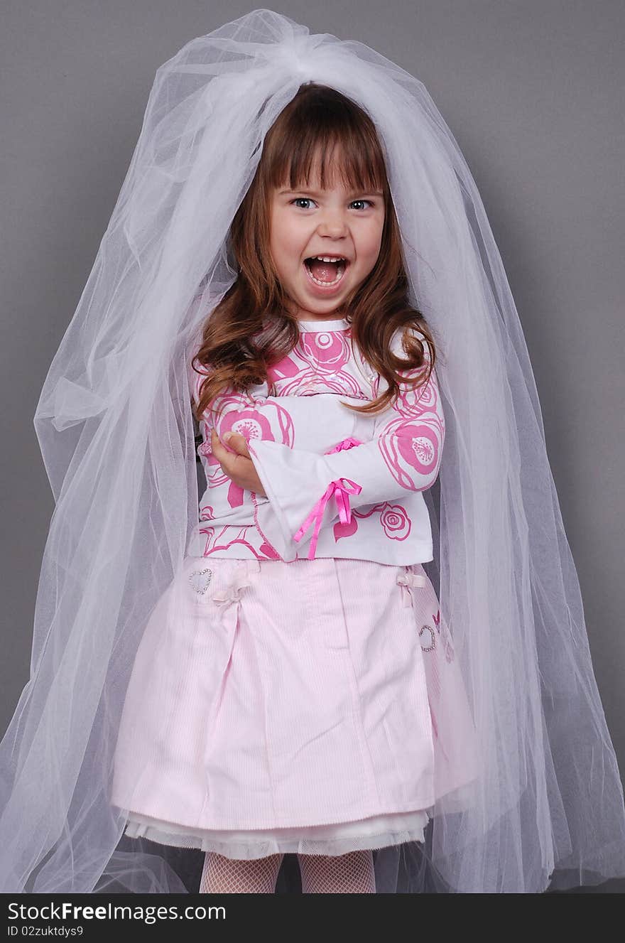 Pretty little girl in a white veil and pink dress