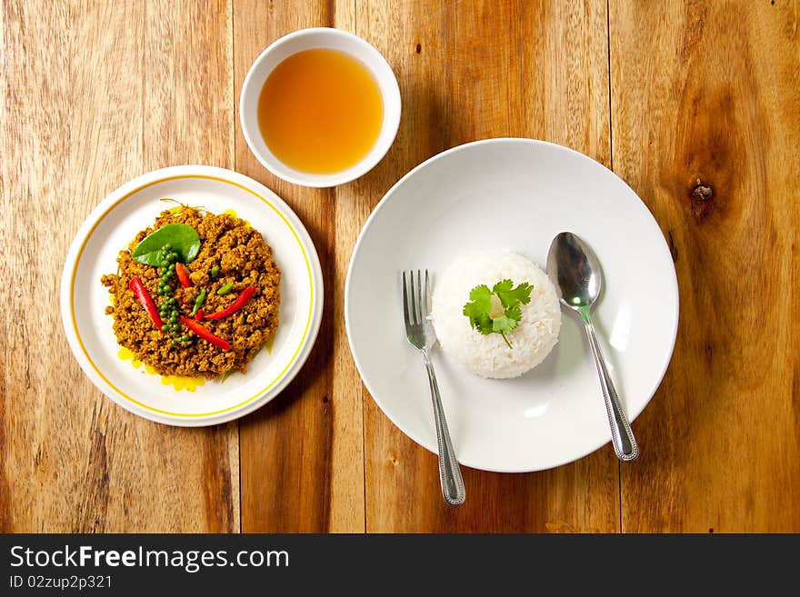 Spicy pork basil with rice and soup on wood background, thai food. Spicy pork basil with rice and soup on wood background, thai food.