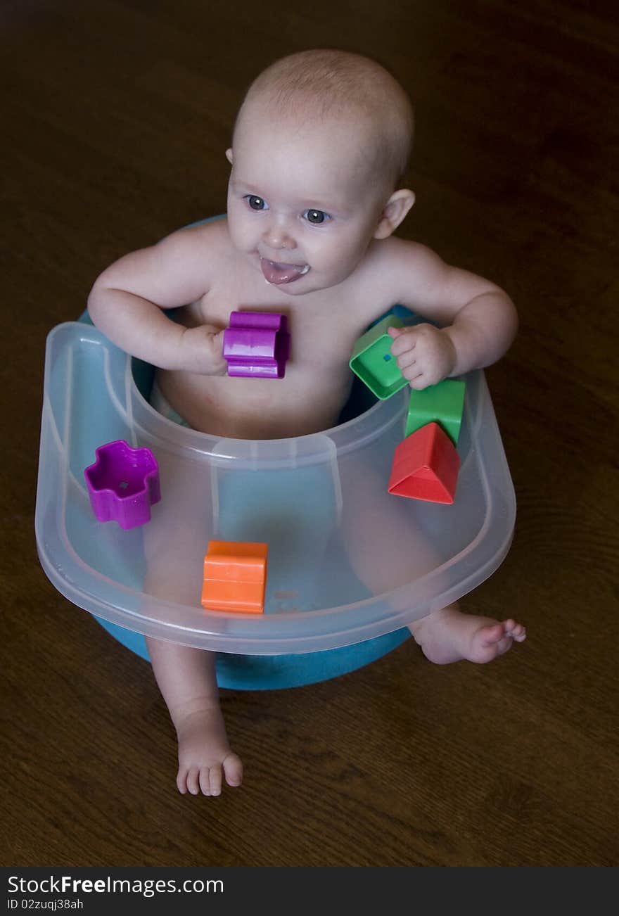 Top down view of baby sitting in chair with tray and playing with blocks. Top down view of baby sitting in chair with tray and playing with blocks.