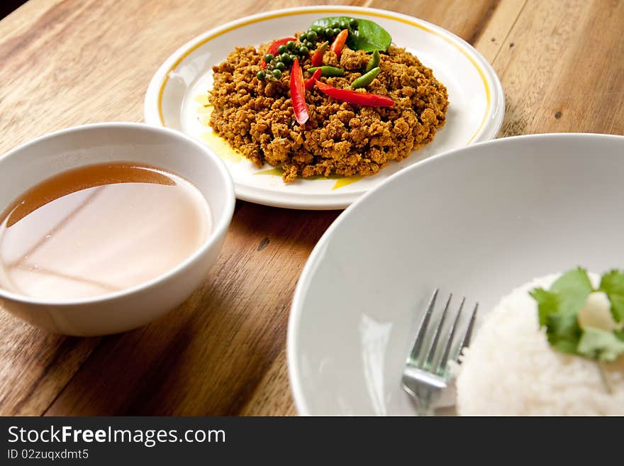 Spicy pork basil with rice and soup on wood background,thai food. Spicy pork basil with rice and soup on wood background,thai food.