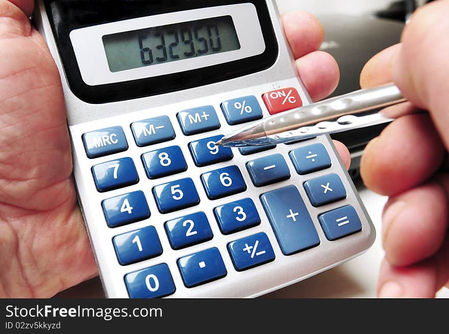 Calculator and ball point in hands of a business man