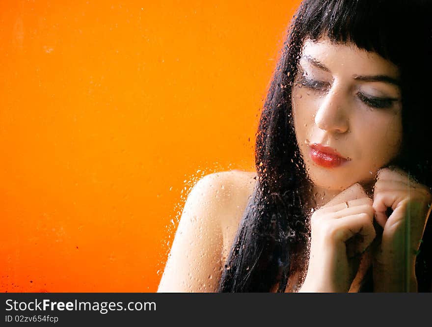 Woman behind glass with rain drops