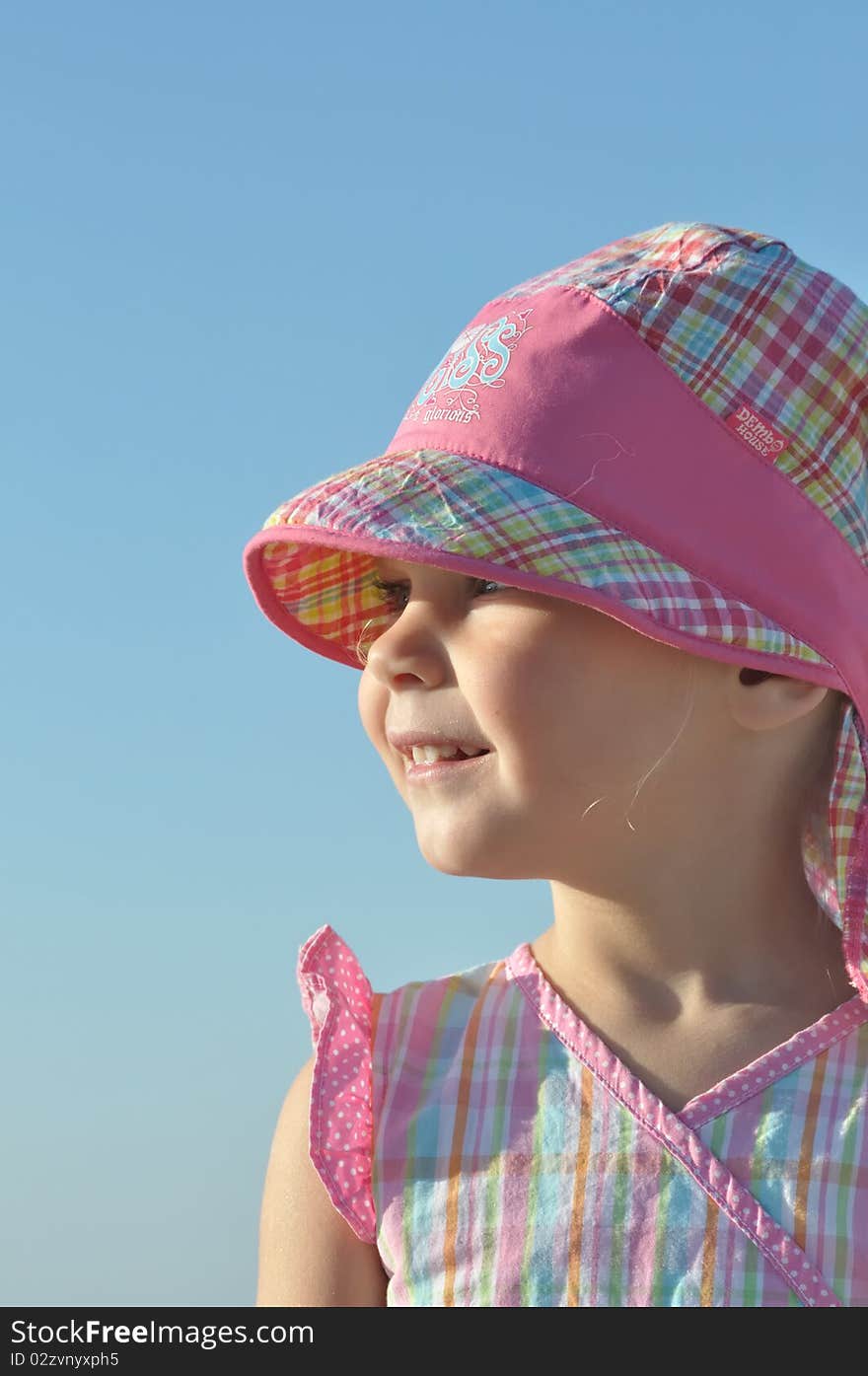 Smiling little girl in pink hat looking afar. Smiling little girl in pink hat looking afar