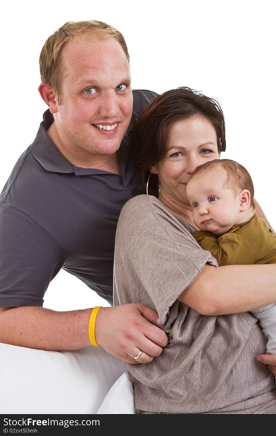 Young happy couple on a couch with their baby over white background. Young happy couple on a couch with their baby over white background.