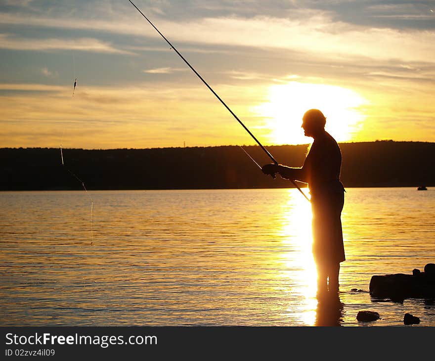 Man fishing on the coast of sea in sunset. Man fishing on the coast of sea in sunset