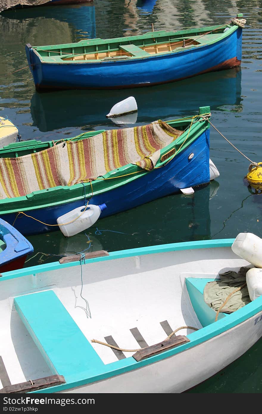 Close up of three small, brightly painted boats floating in a harbour. Close up of three small, brightly painted boats floating in a harbour.