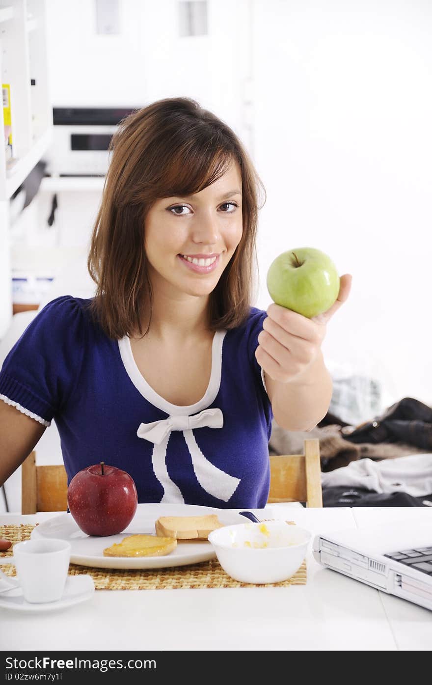 Young woman in breakfast, eating green apple, smiling and looking in camera. Young woman in breakfast, eating green apple, smiling and looking in camera