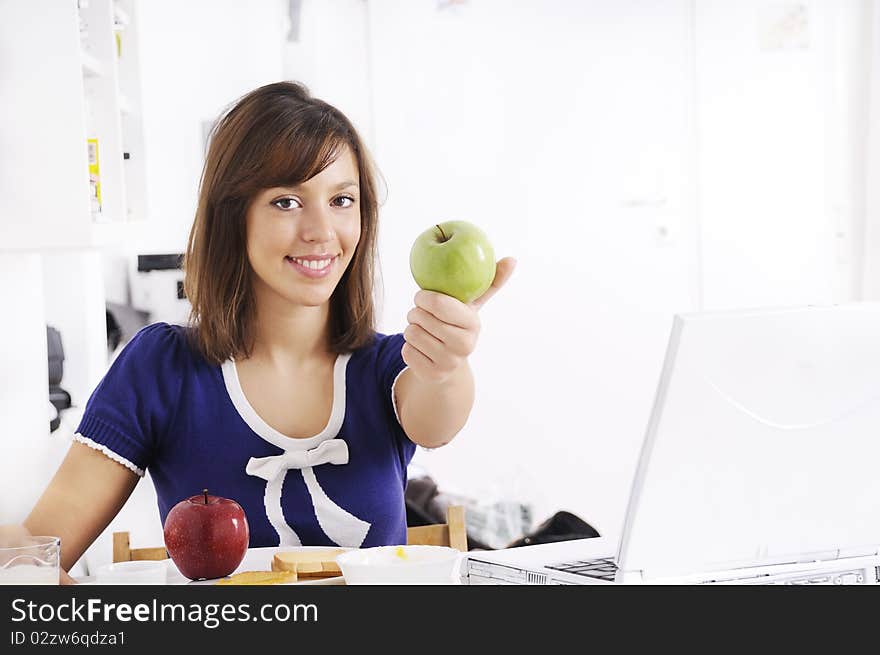 Young woman in breakfast, eating green apple, smiling and looking in camera. Young woman in breakfast, eating green apple, smiling and looking in camera