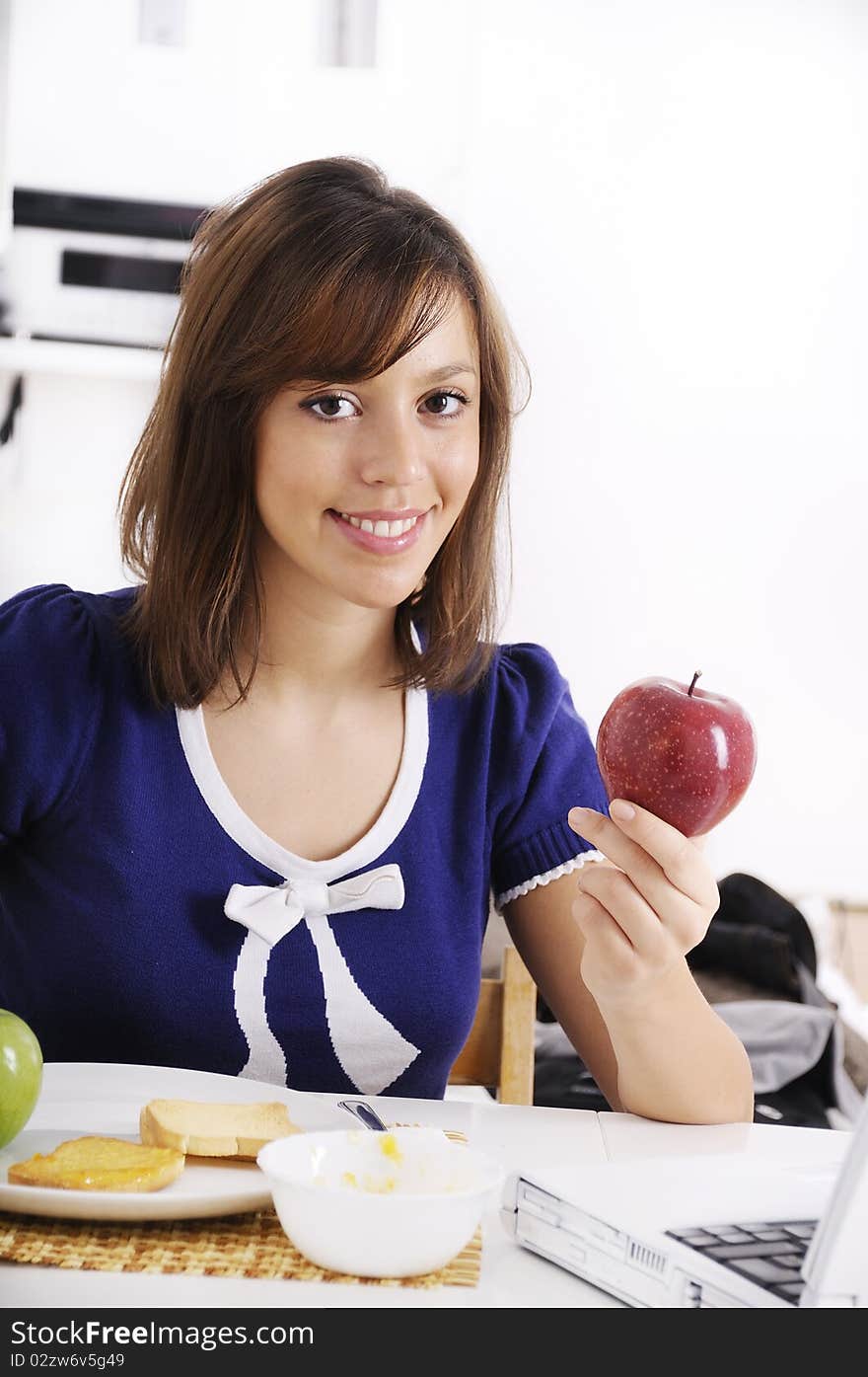 Young woman in breakfast, eating red apple, smiling and looking in camera. Young woman in breakfast, eating red apple, smiling and looking in camera