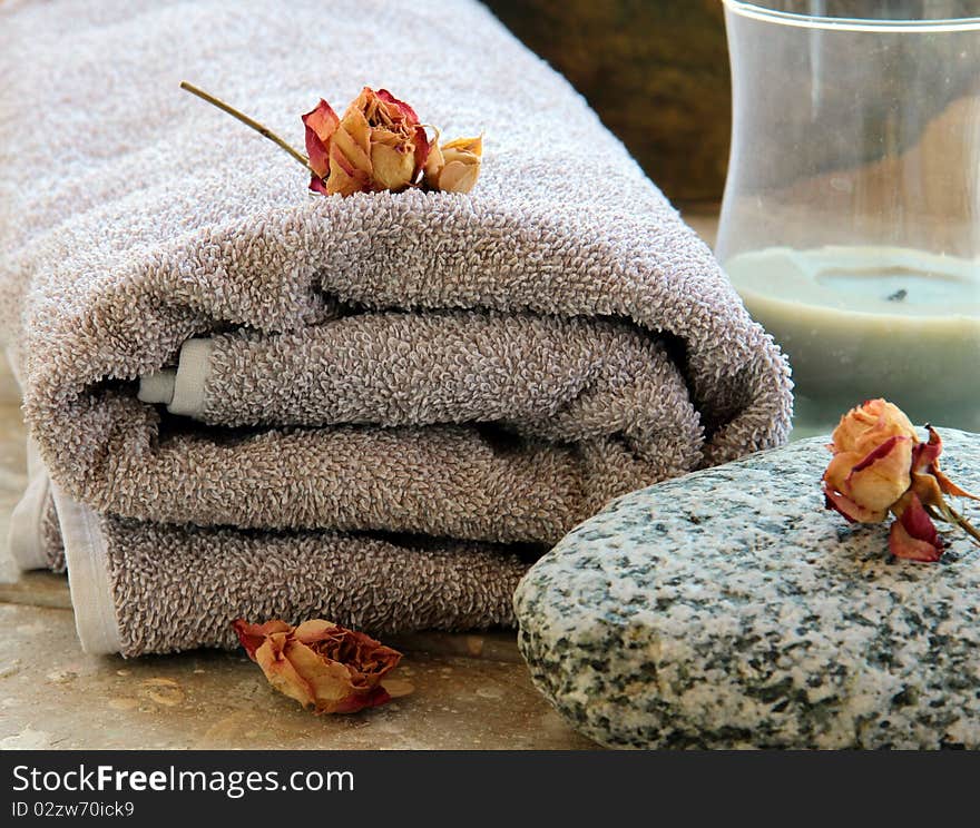 Gray towel with a rock and a candle and dry roses