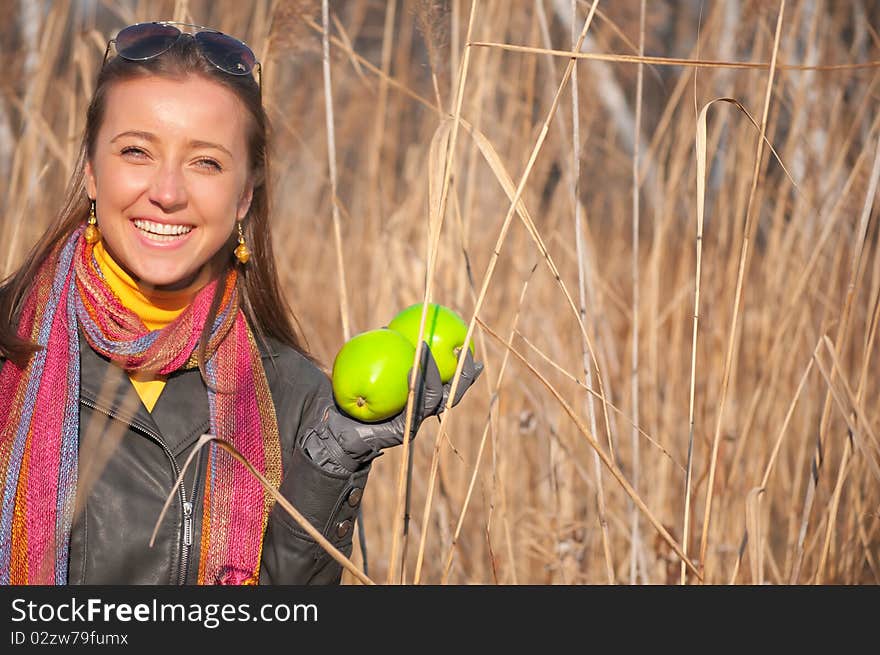 Beautiful young smiling woman with green apples in the high dry grass. Beautiful young smiling woman with green apples in the high dry grass