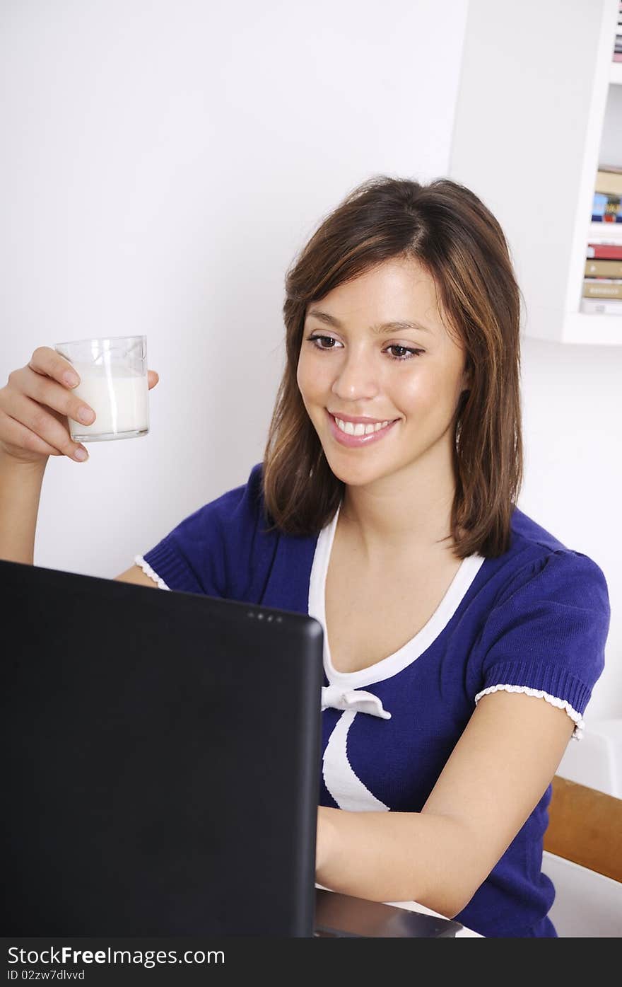 Young woman in breakfast, drinking milk and using laptop. Young woman in breakfast, drinking milk and using laptop