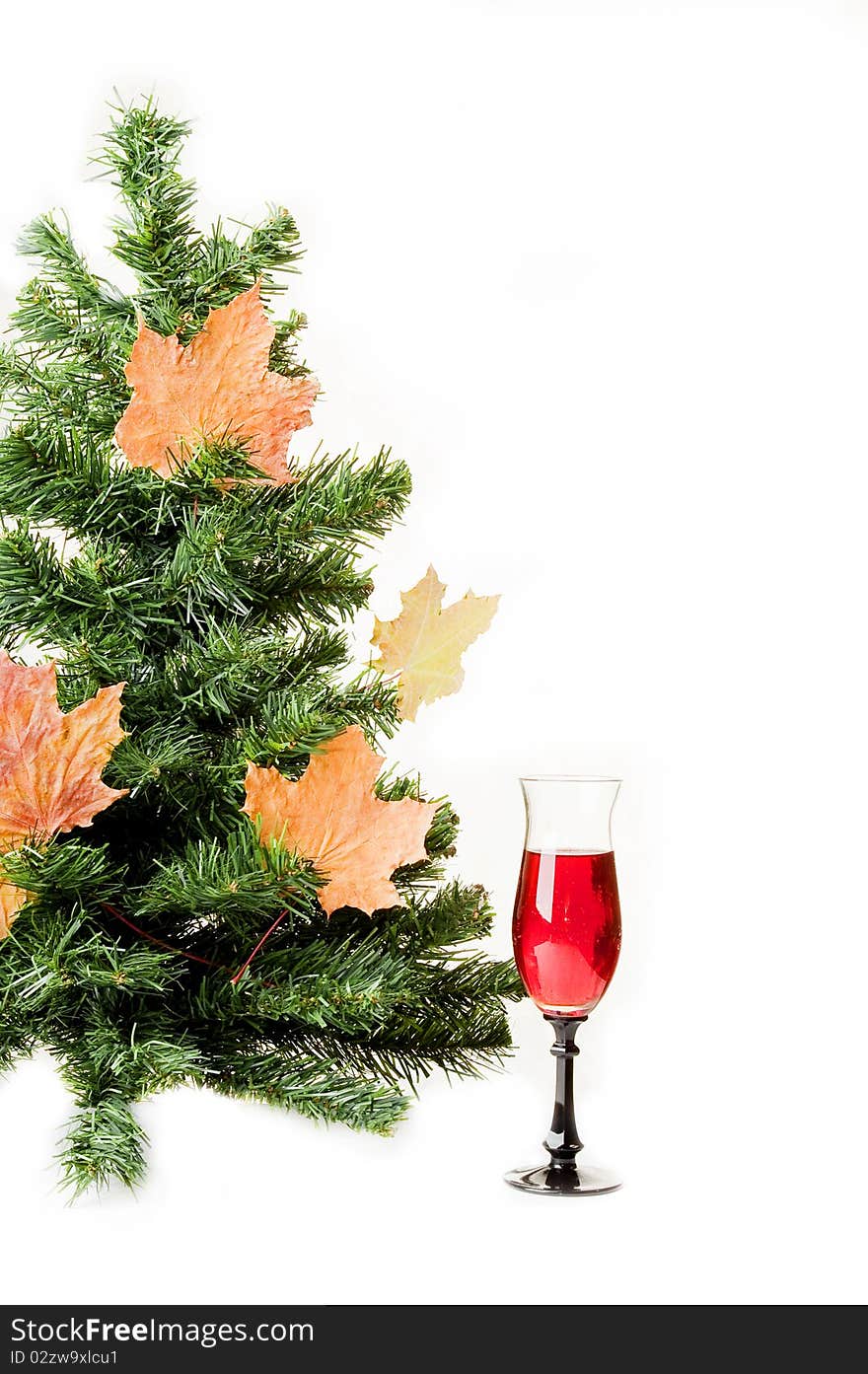 Christmas fur-tree on a white background decorated with autumn maple leaves and a wine glass. Christmas fur-tree on a white background decorated with autumn maple leaves and a wine glass