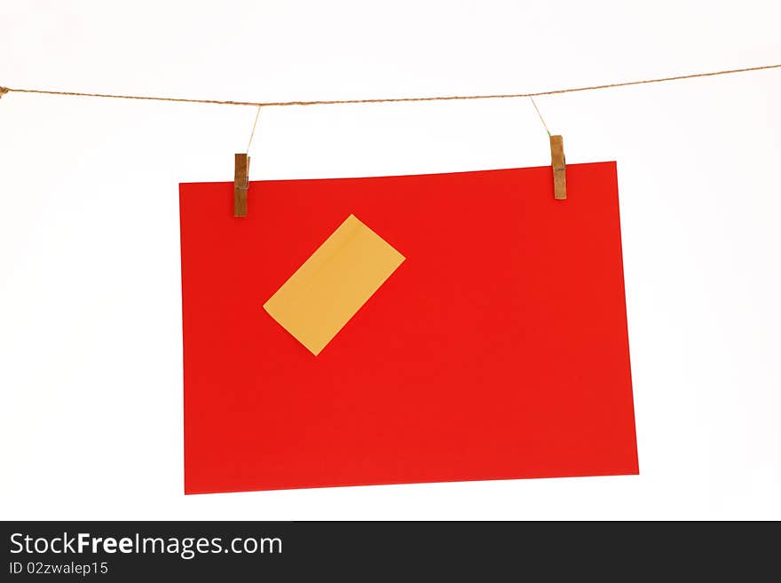 Red paper sheet and yellow on a clothes line. Isolated on white background.