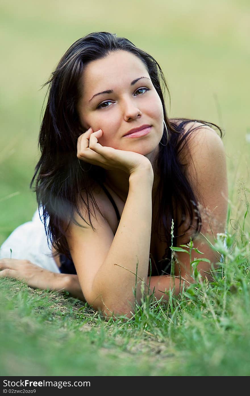 Young pretty girl lying on green grass