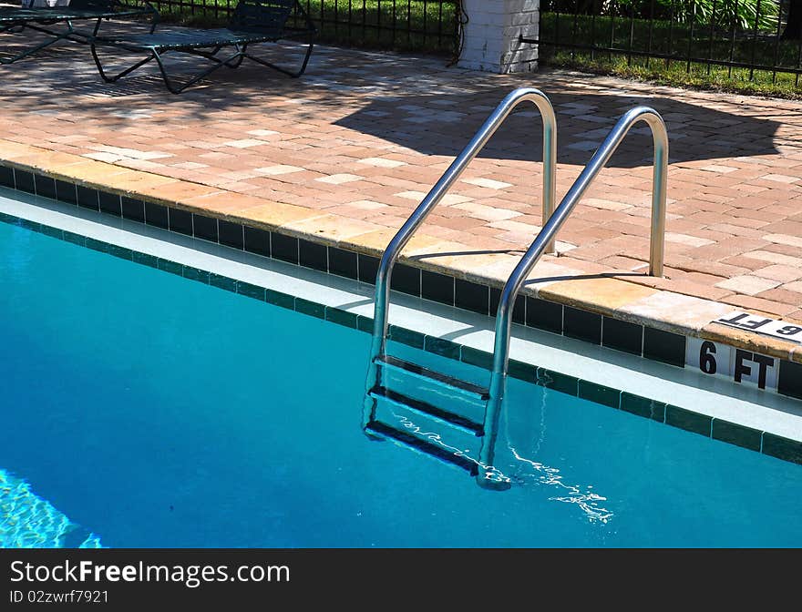 A silver metal swimming pool ladder and a brick pattern background