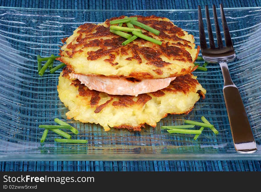 Roesti and grilled salmon with chives over a glass dish